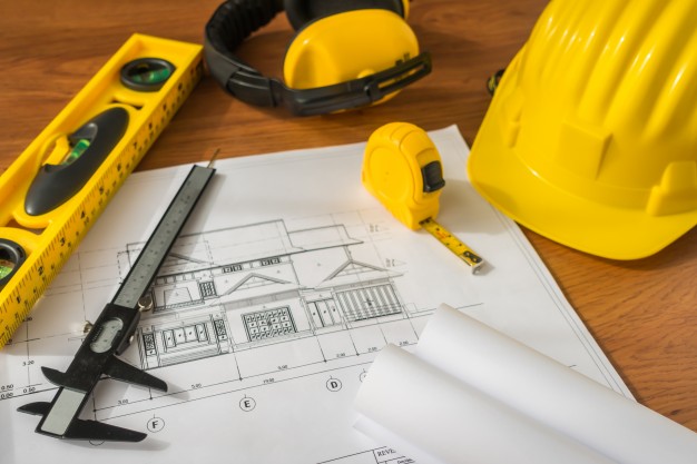 construction-plans-with-yellow-helmet-and-drawing-tools-on-bluep_1232-2939